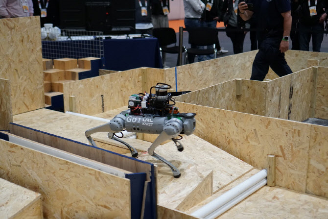 Figure 1: DreamWaQer participating in the Autonomous Quadruped Robot Challenge (AQRC) held at IEEE ICRA 2023. Leveraging the robust controller, DreamWaQ, the robot showcases the ability to overcome terrains with irregular shapes. The autonomous walking system, DreamSTEP, efficiently guides DreamWaQer along safe and expedient paths.